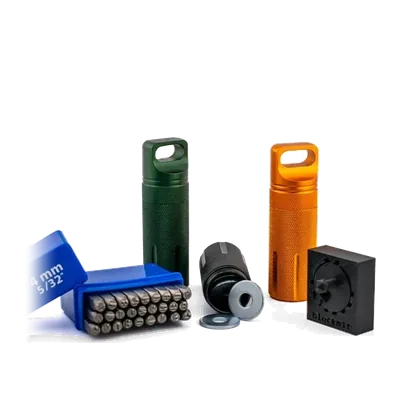 Steel Seed Set: aluminium tubes in green, orange and black with the steel letter stamps and the stamping block
